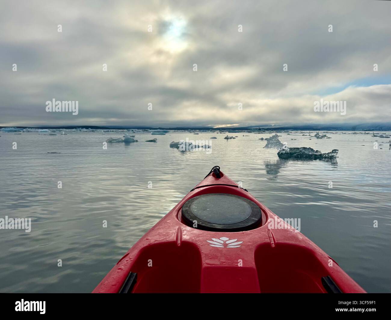 A kayak drifting through floating icebergs in Jokusarlon Glacier Lagoon on a summer evening. - Smartphone Captured Stock Image