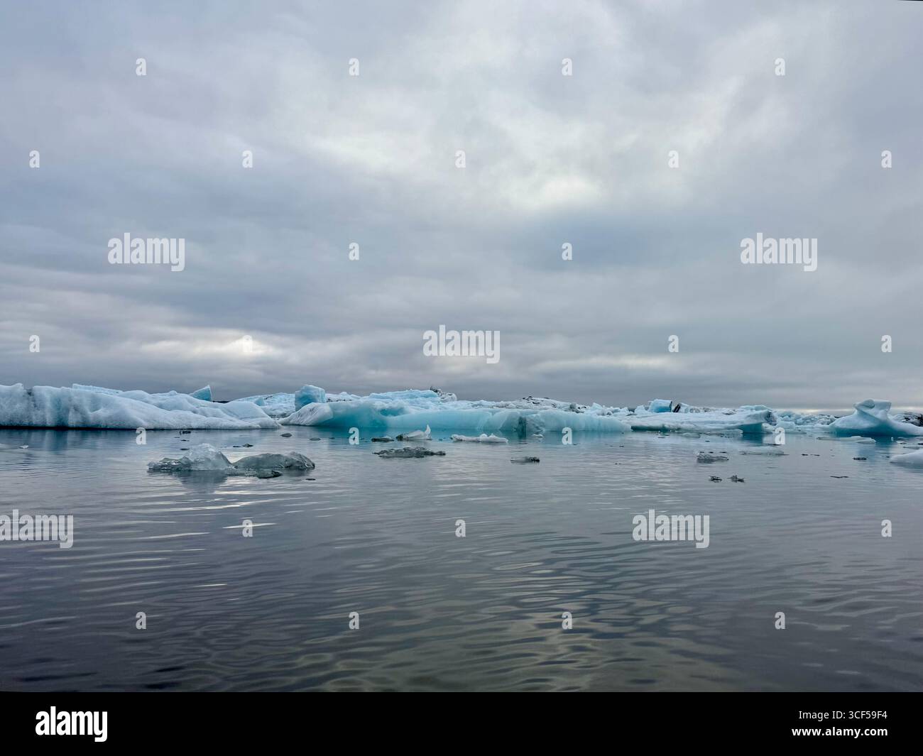Hint of a pale early evening summer sunset reflecting accross the masses of blue ice and into the glacier lagoon. - Smartphone Captured Stock Image