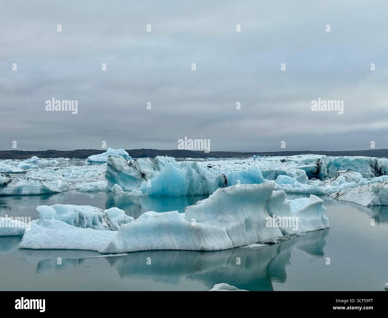 Vibrant blue icebergs with remants of black volcanic ash in Glacier Lagoon, - Smartphone Captured Stock Image