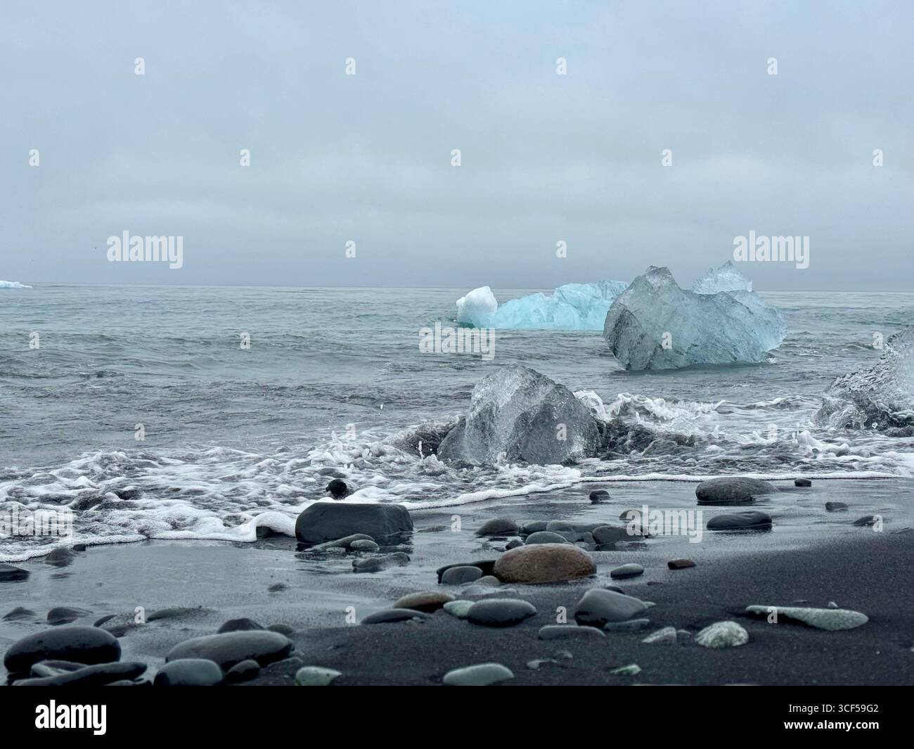Blue icebergs and white icebergs laden with volcanic ash afloat in the Atlantic Ocean at Breidamerkursandur, otherwise known as 'Diamond Beach' - Smartphone Captured Stock Image