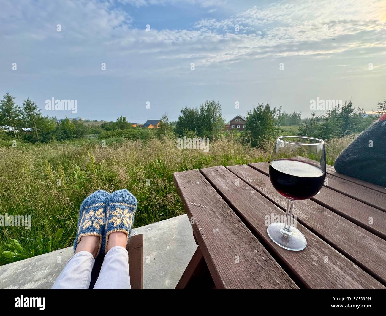 Relaxing outdoors in north Iceland in the summer with a glass of wine and Iceland hand made sheep's wool slippers. - Smartphone Captured Stock Image