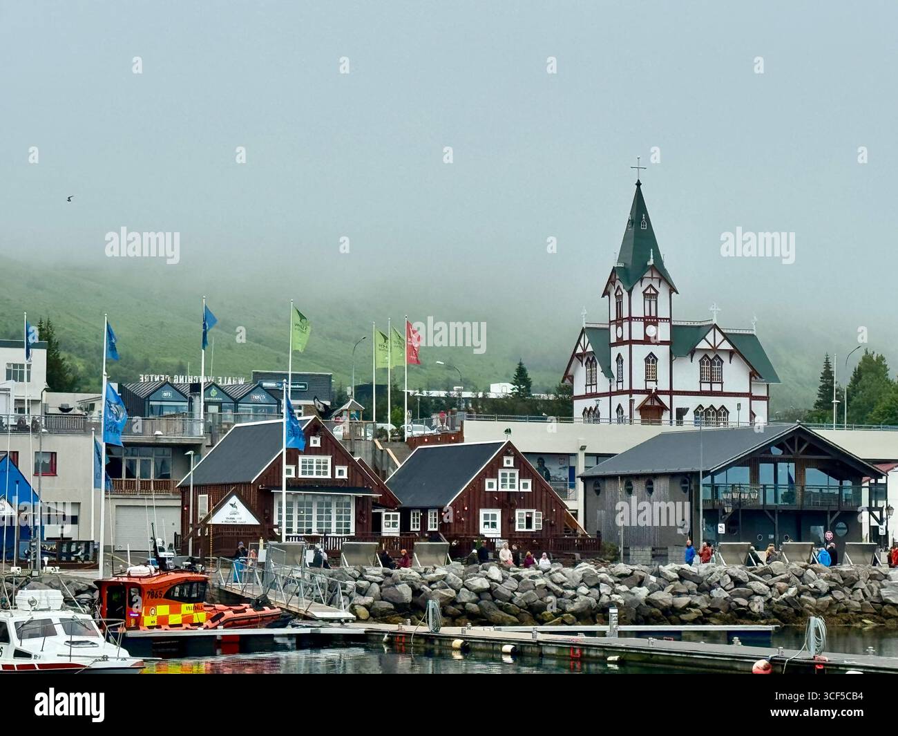 Summer fog decending down the green hills behing on the oldest settlement in Iceland, the charming Husavik fishing village. - Smartphone Captured Stock Image