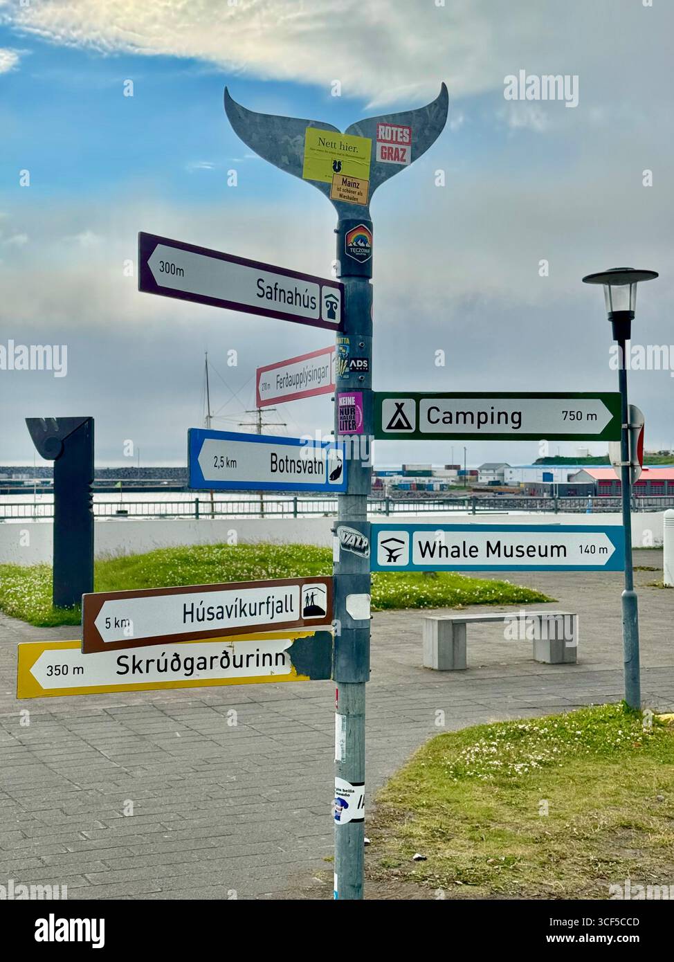 Sign post topped with a whale fluke at Husavik harbor pointing the way to popular attractions in the area. - Smartphone Captured Stock Image