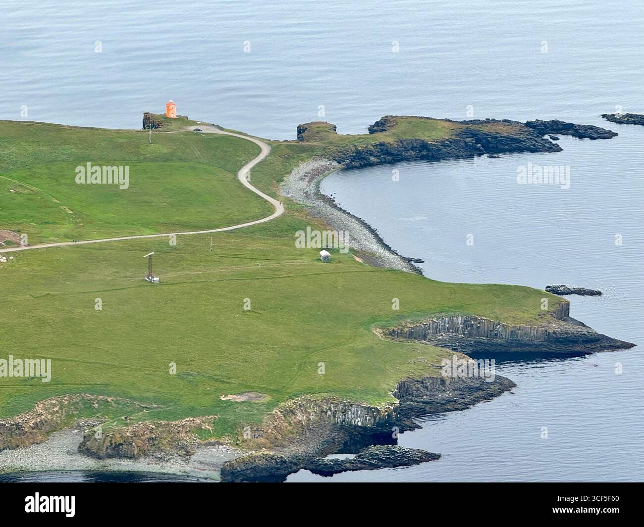 The orange Grimsey Lighthouse, on the southeast corner of the island, pops out against the lush green land and blue North Atlantic Ocean. - Smartphone Captured Stock Image