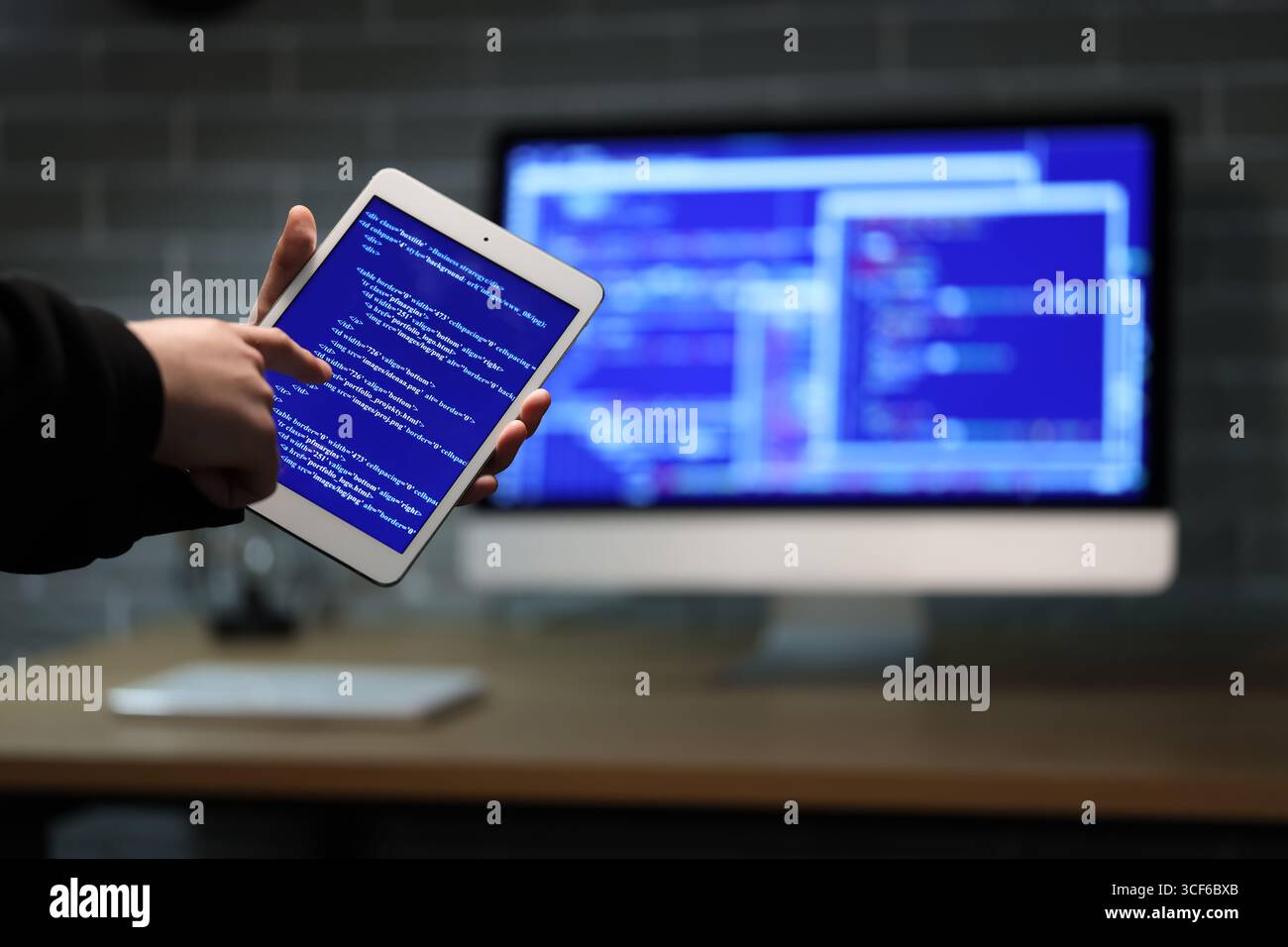 Hacker using tablet computer in dark room, closeup Stock Photo