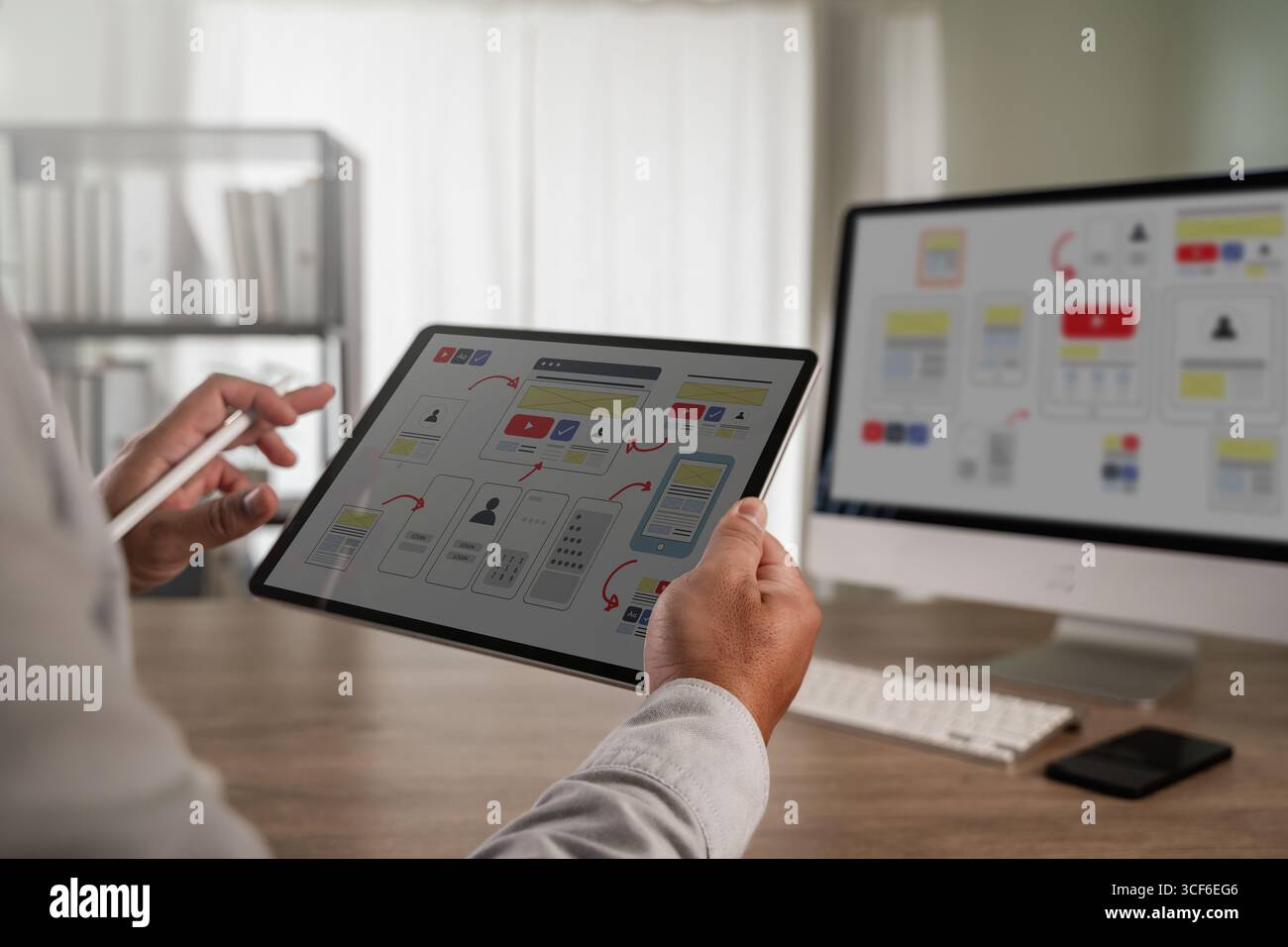 UX UI design process concept showing a designer using a tablet to work on interface wireframes and user flow diagrams, representing web development, m Stock Photo
