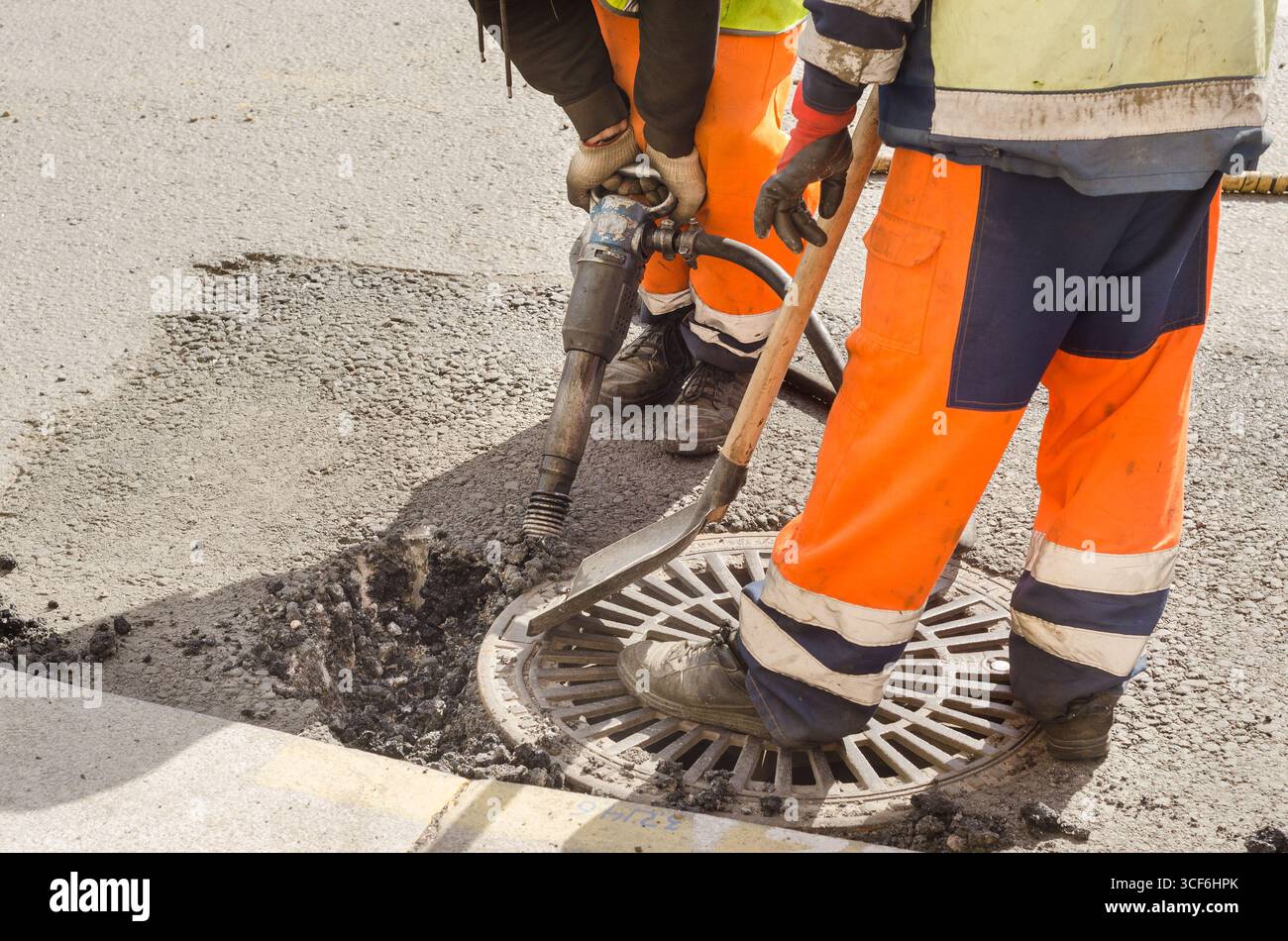 worker uses jackhammer to break road asphalt Stock Photo