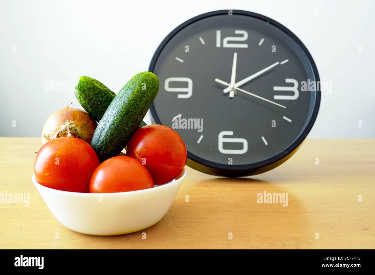 Fresh vegetables in white bowl next to clock - efficient meal planning ...