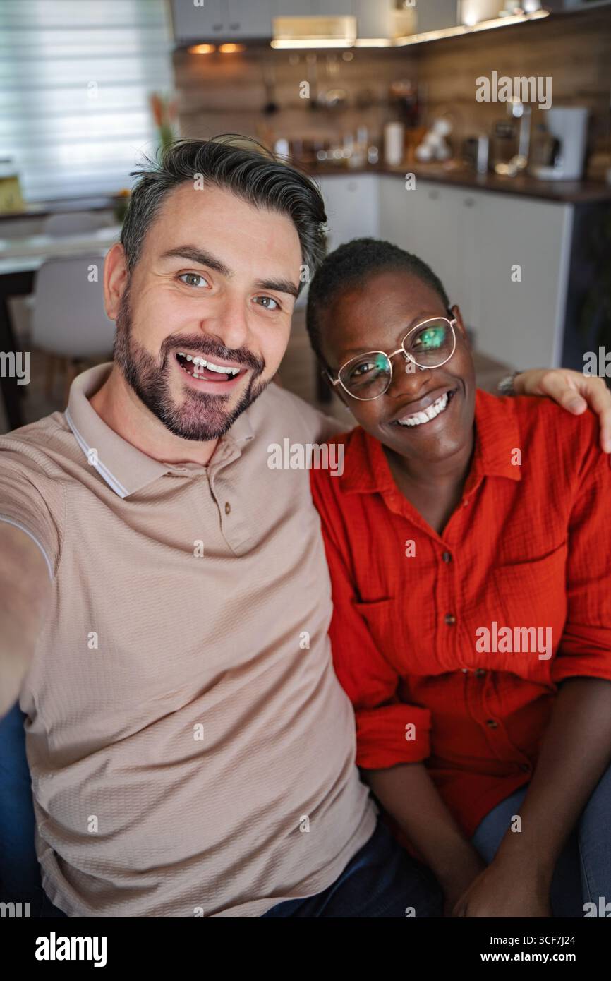 Happy multi-ethnic couple taking a selfie at home Stock Photo