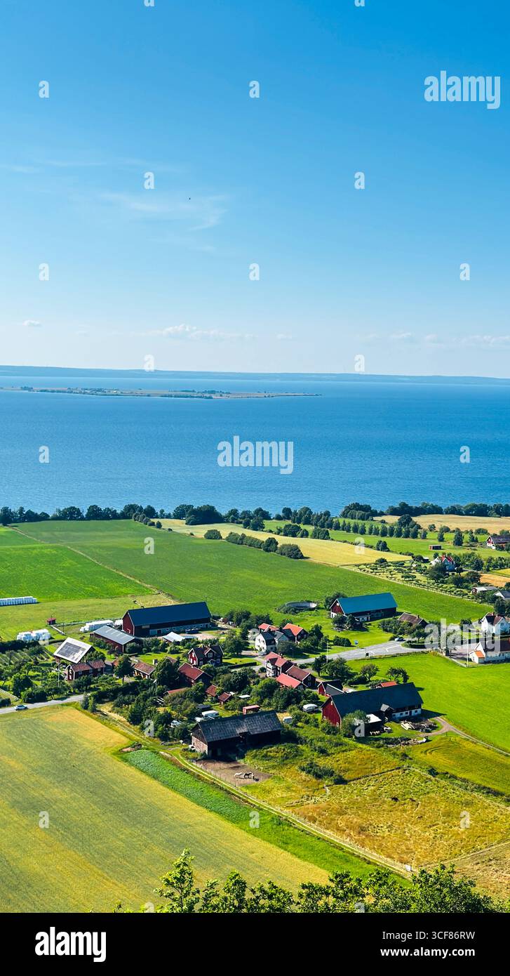 Aerial view of rural countryside with farmlands and traditional houses by the sea, Scandinavia - Smartphone Captured Stock Image