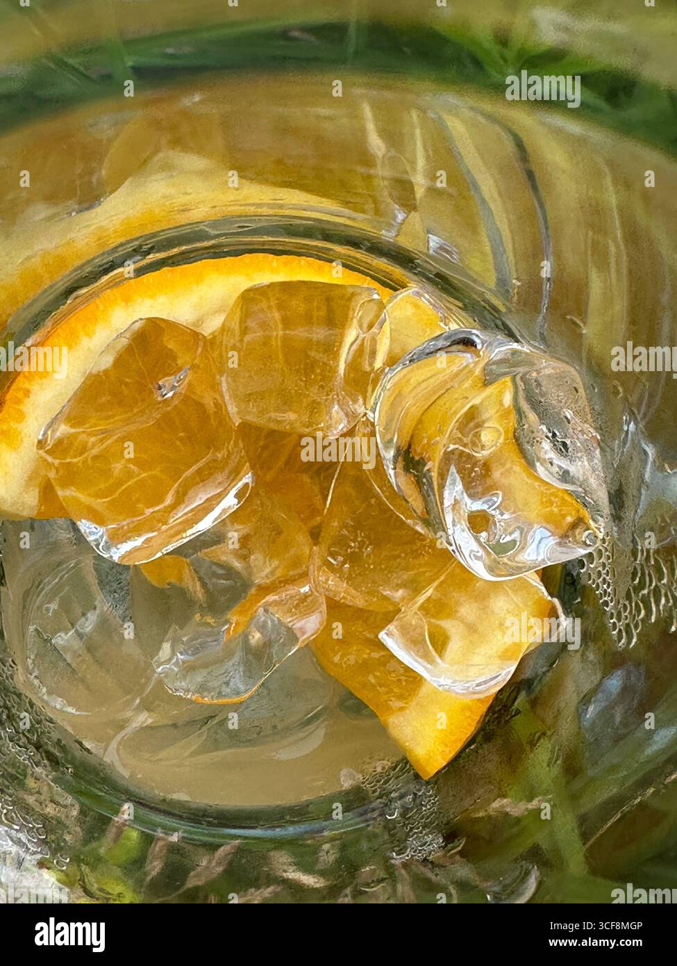 Macro close-up of a refreshing drink with ice cubes and an orange slice inside a glass. Concept of summer, freshness, and healthy lifestyle. - Smartphone Captured Stock Image