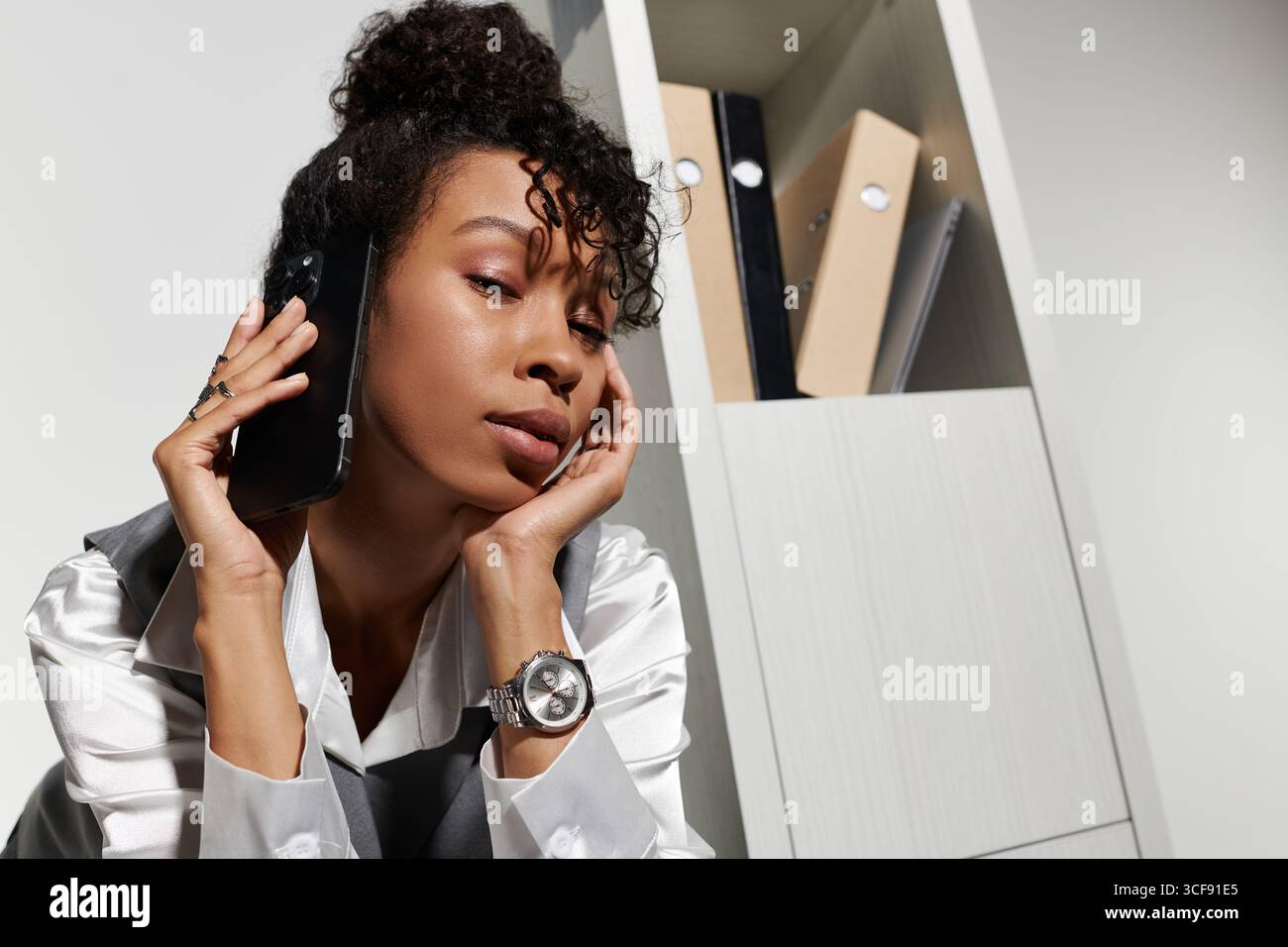 A young woman in business attire talks thoughtfully on her phone. Stock Photo