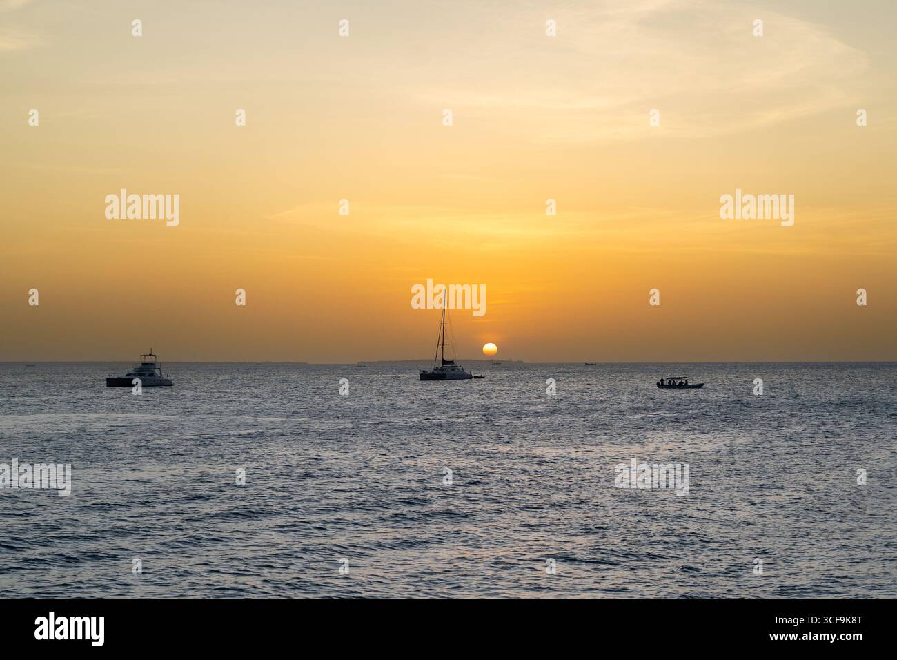 Golden Zanzibar sunset with sailboats and catamarans drifting across the calm Indian Ocean. Stock Photo