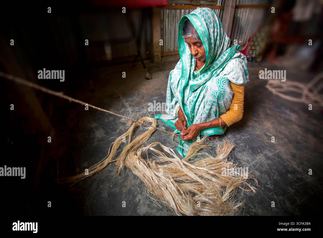 An old age woman is making a rope from the banana tree fibers in her ...