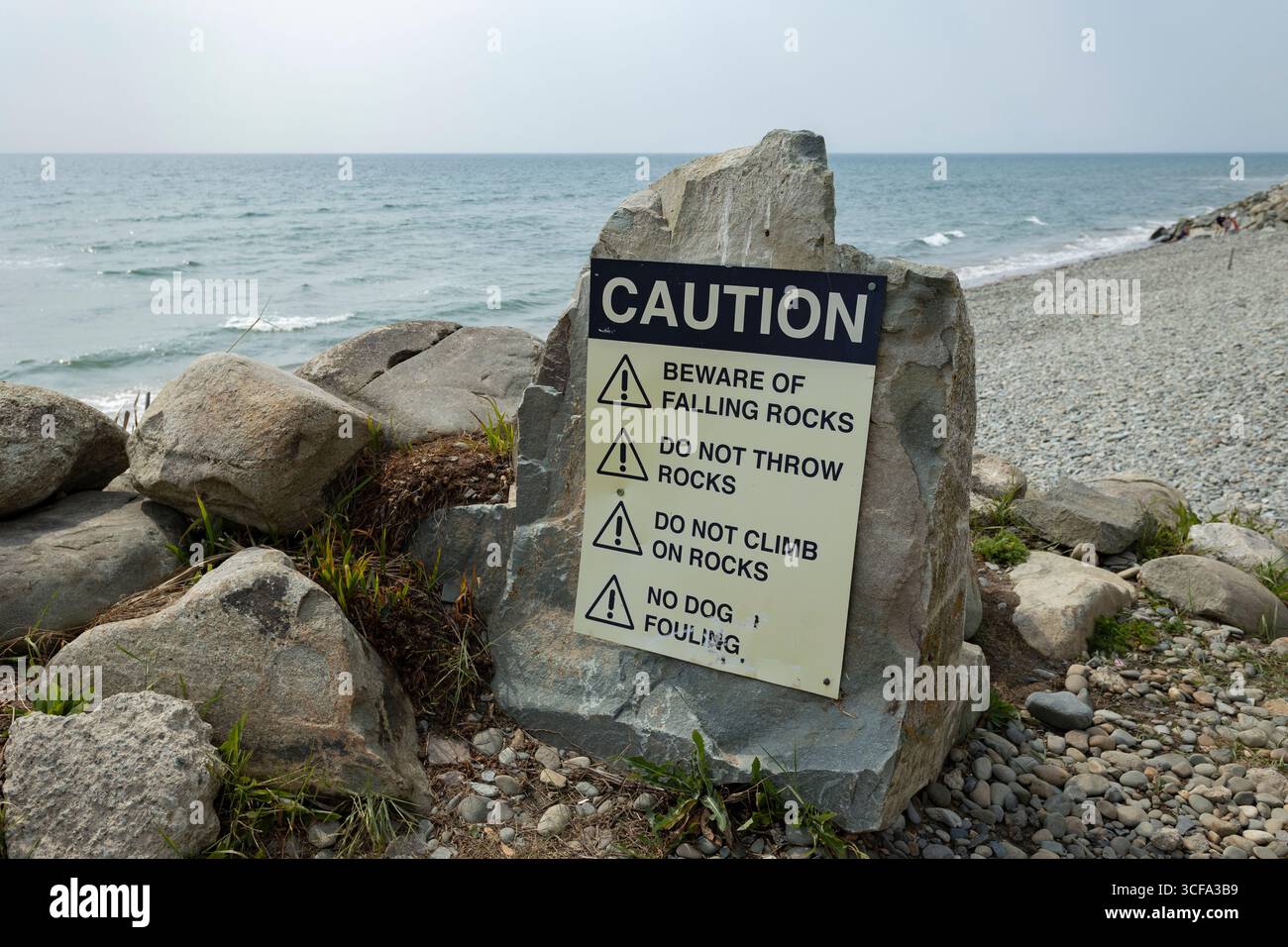 Caution Sign by a Rocky Seashore Warning About Potential Hazards Stock ...