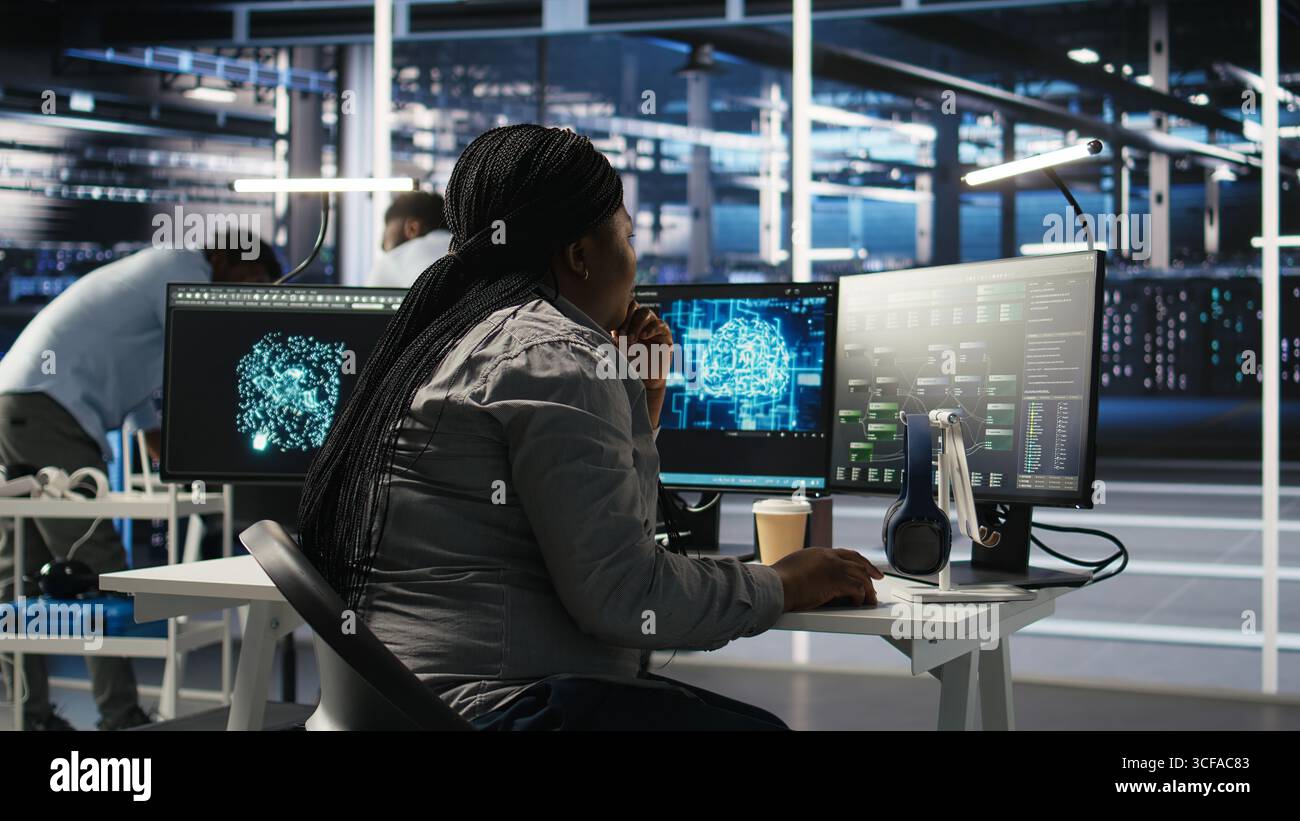 Data center software developer using artificial intelligence deep learning models to configure hardware. IT professional works on AI programming language in server farm, optimizing system, camera A Stock Photo