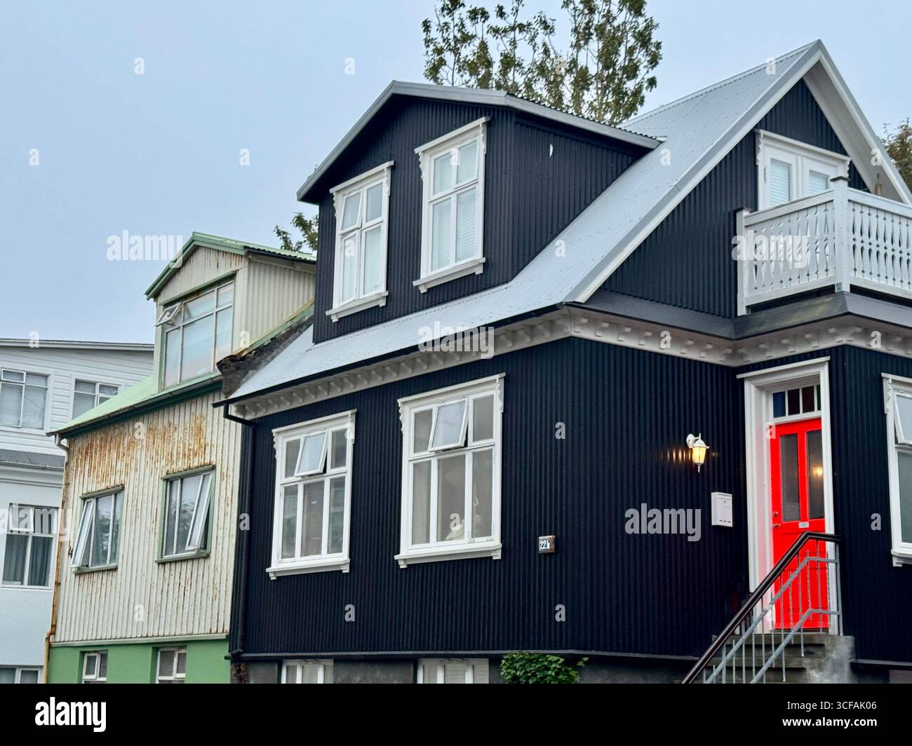 Red door stands out boldy against the black paint on the building. - Smartphone Captured Stock Image