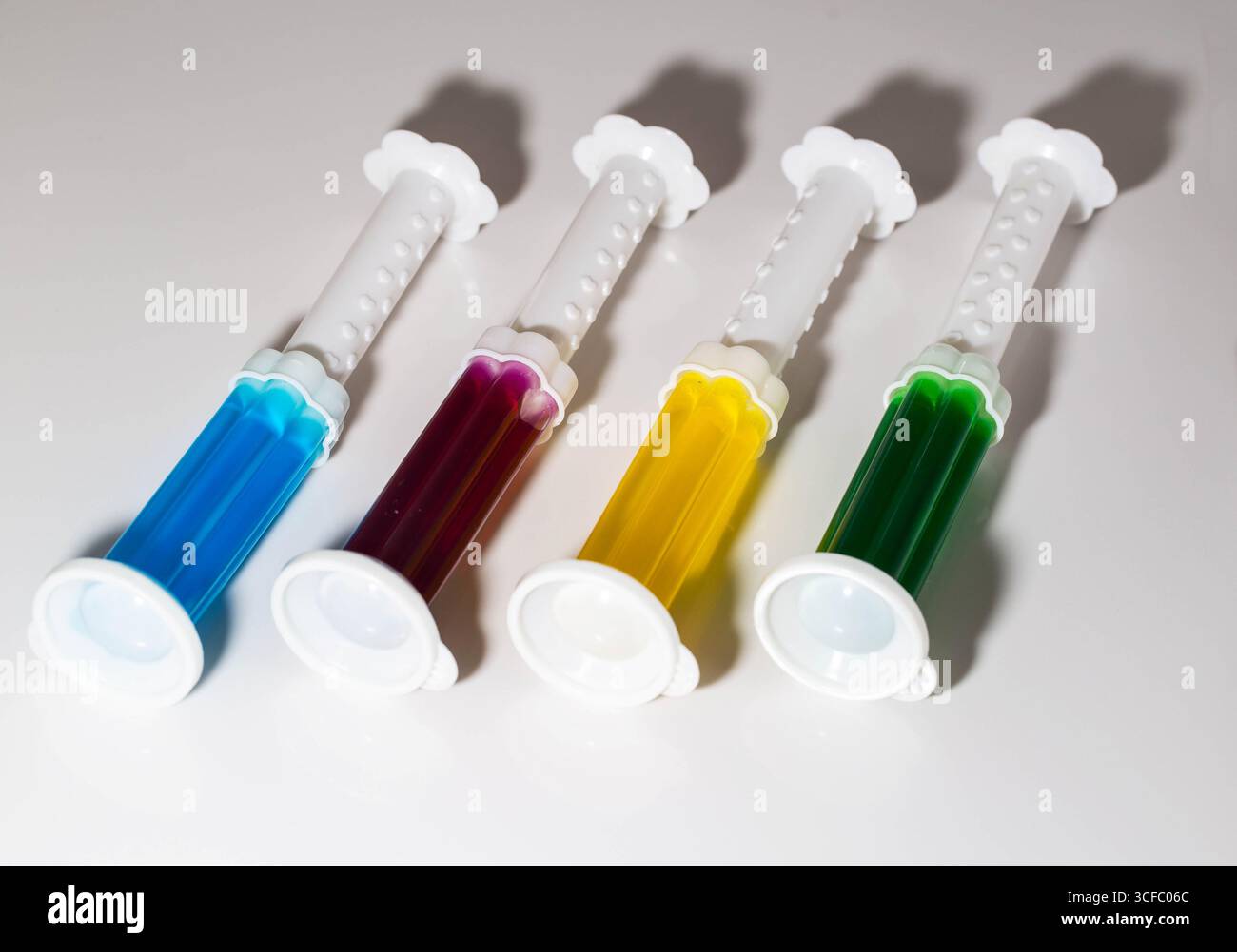 A set of multi-colored syringes with different scents on the toilet ...