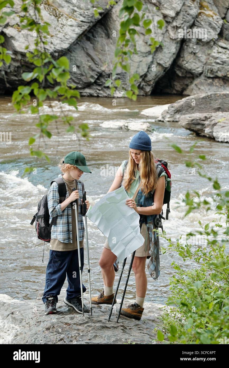 Mother Guiding Boy While Reading Map Outdoors Stock Photo