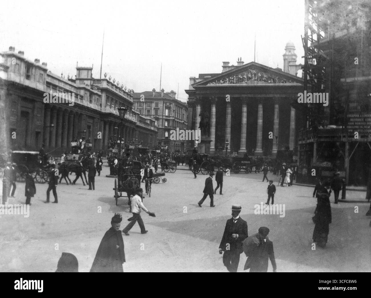 London, England. circa.1903 – An interesting Edwardian photograph of Royal Exchange and the Bank of England on Threadneedle Street in the City of London. The image shows the Bank of England in its original configuration before it was redesigned and altered in 1926. On the right is scaffolding erected during the construction of the building known as 1 Cornhill. In front of the Royal Exchange is the statue of the Duke of Wellington. The street is busy with pedestrians, horse-drawn omnibuses, carriages and a cyclist. Stock Photo