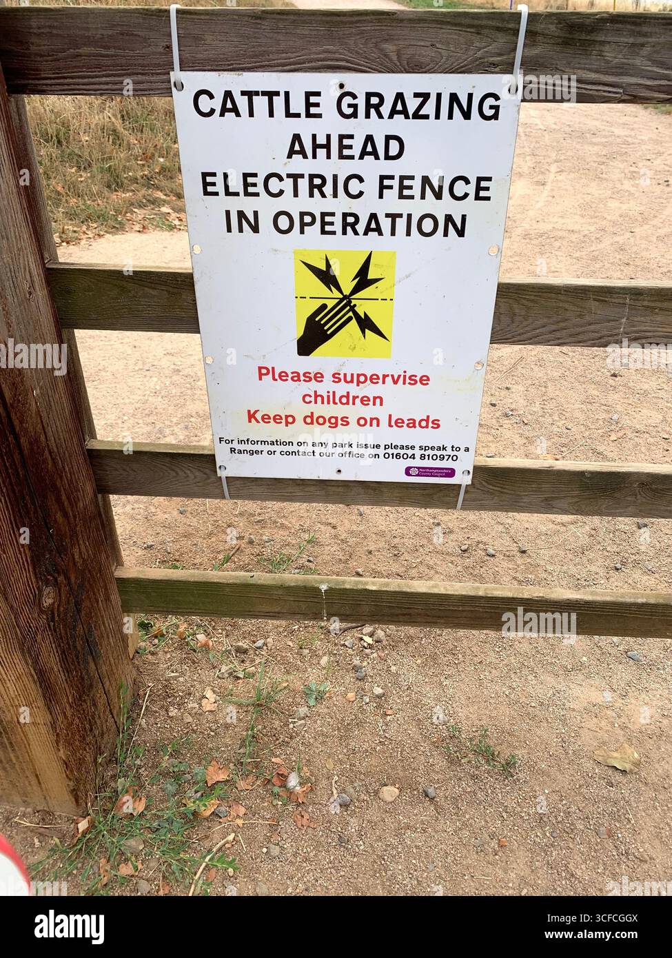 Electric fence sign solar powered power Cattle grazing fencing power fencing wires wire cable stored danger shock shocks place field safety - Smartphone Captured Stock Image