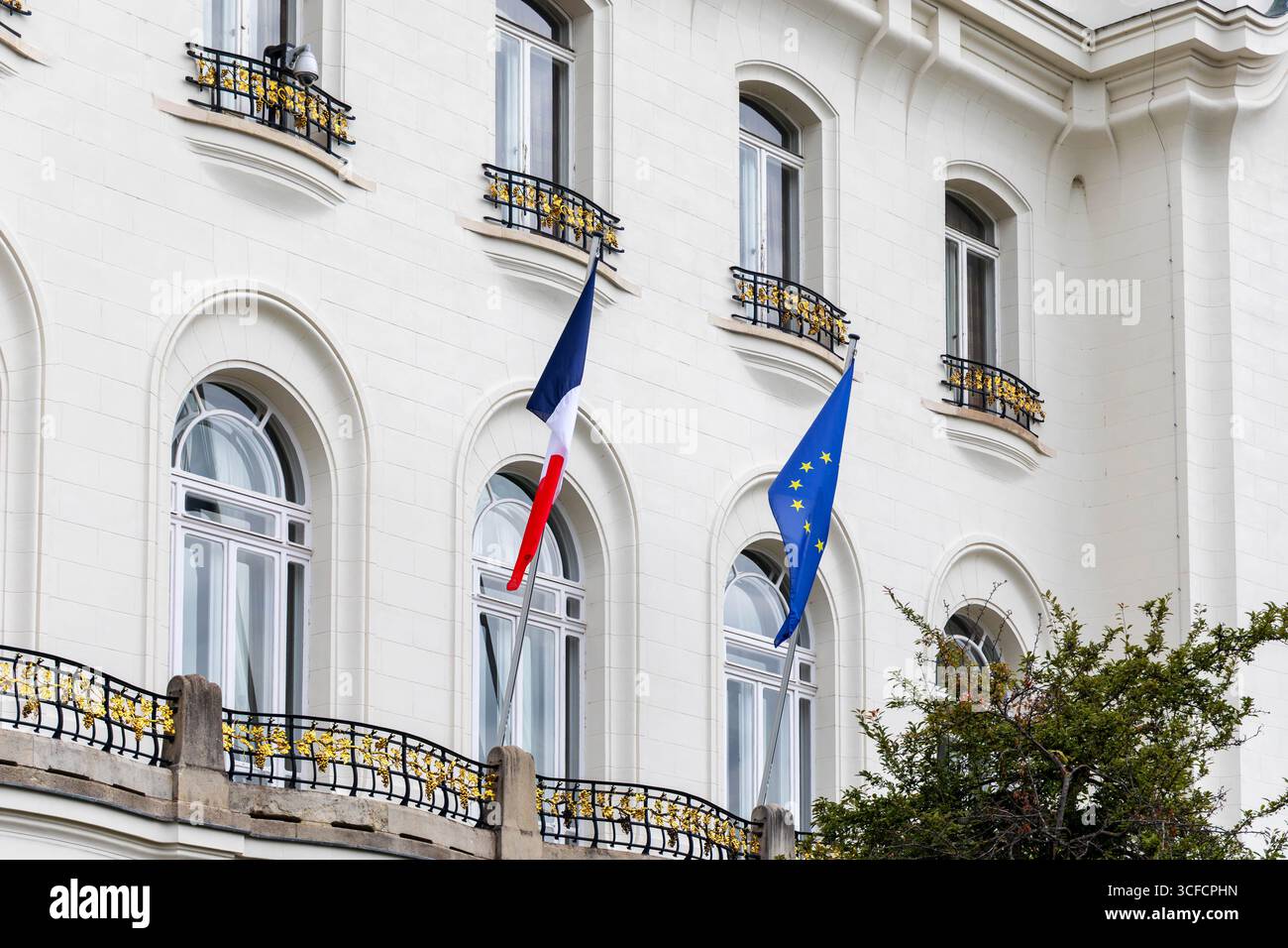 French and European Union flags on embassy building. Exterior view of a white classical building with French and EU flags, likely indicating a Stock Photo