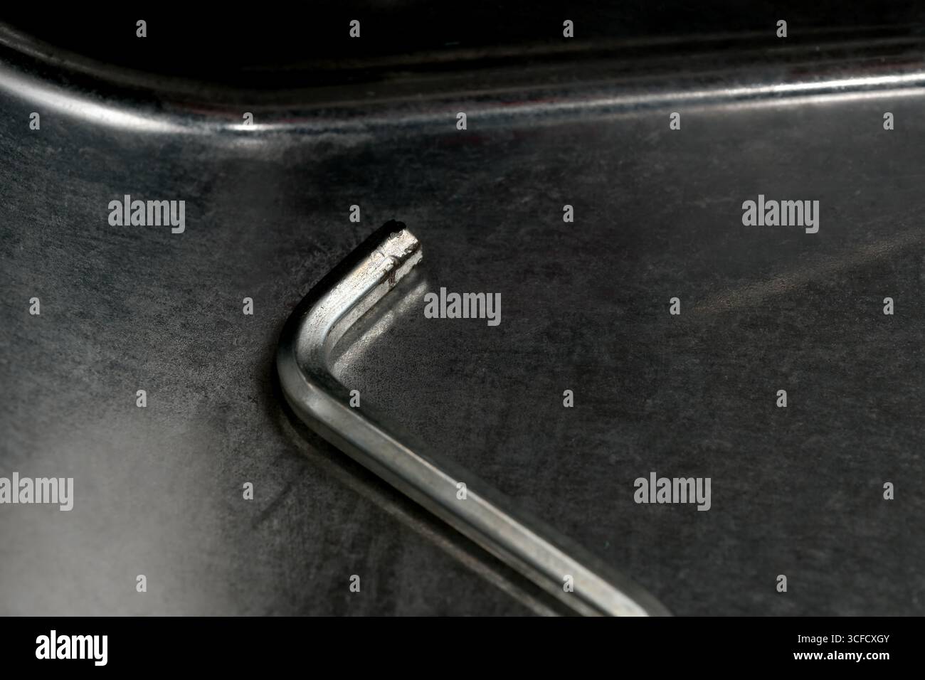 Craftsman uses a metal tool on a polished dark surface in a bright workshop. Stock Photo
