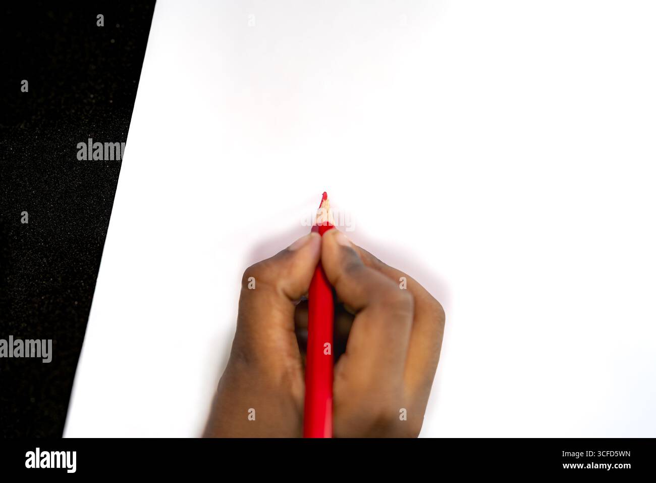 Hand Holding Red Colored Pencil on White Paper Stock Photo