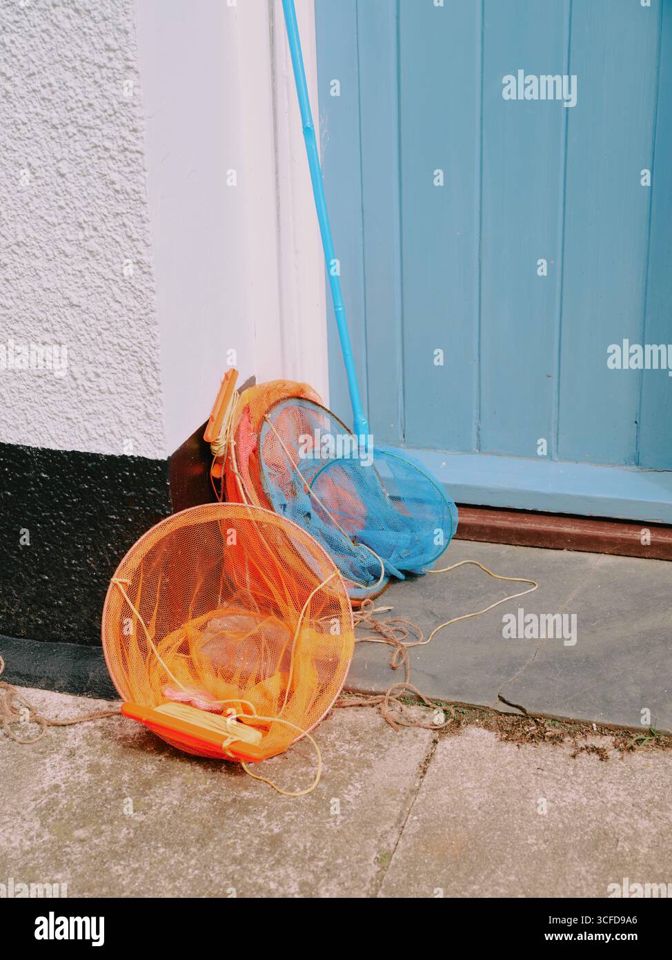 Two colourful childrens fishing nets on the doorstep of a seaside holiday home - staycation summer summertime family holiday uk Stock Photo