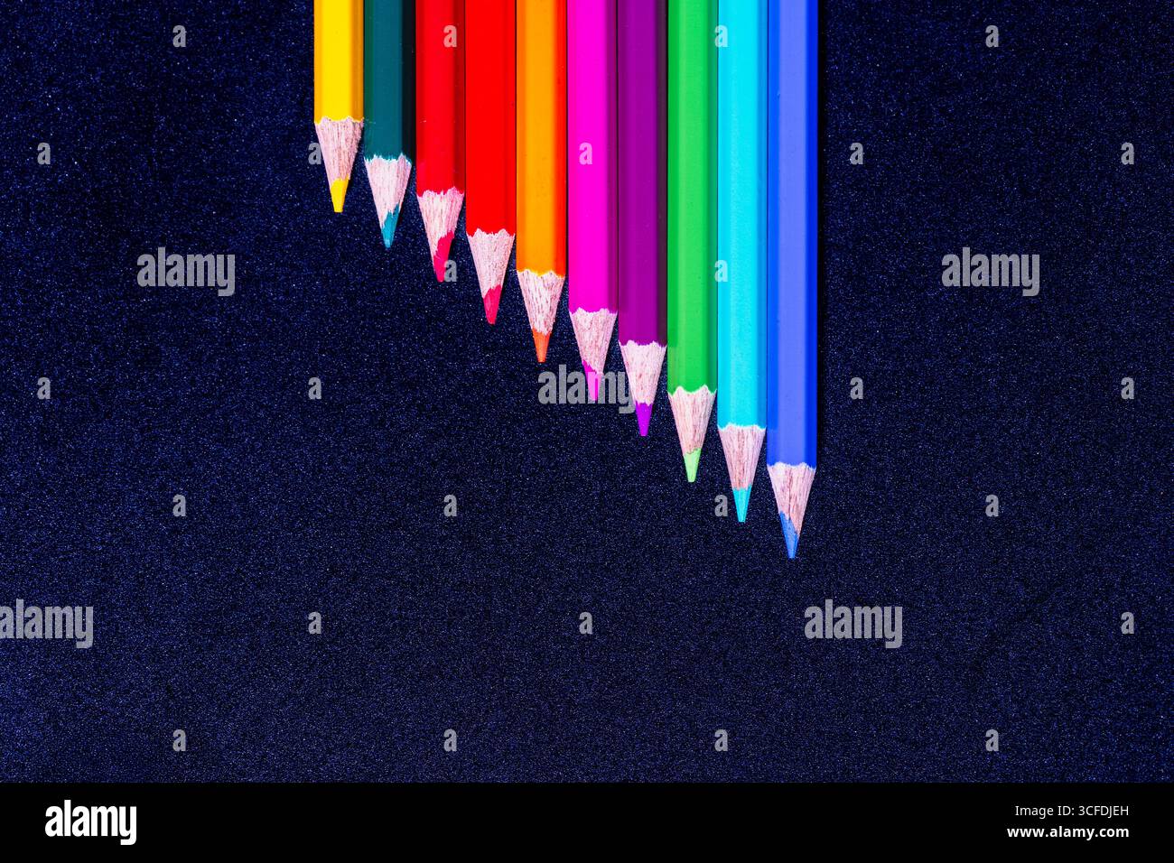 Diagonal Arrangement of Colored Pencils on Dark Textured Background Stock Photo