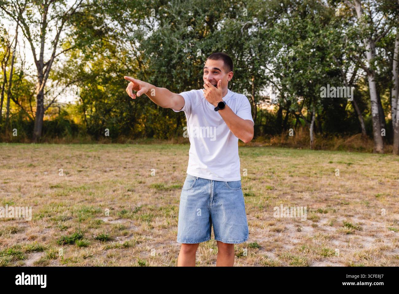 Young man laughing and pointing finger in park Stock Photo