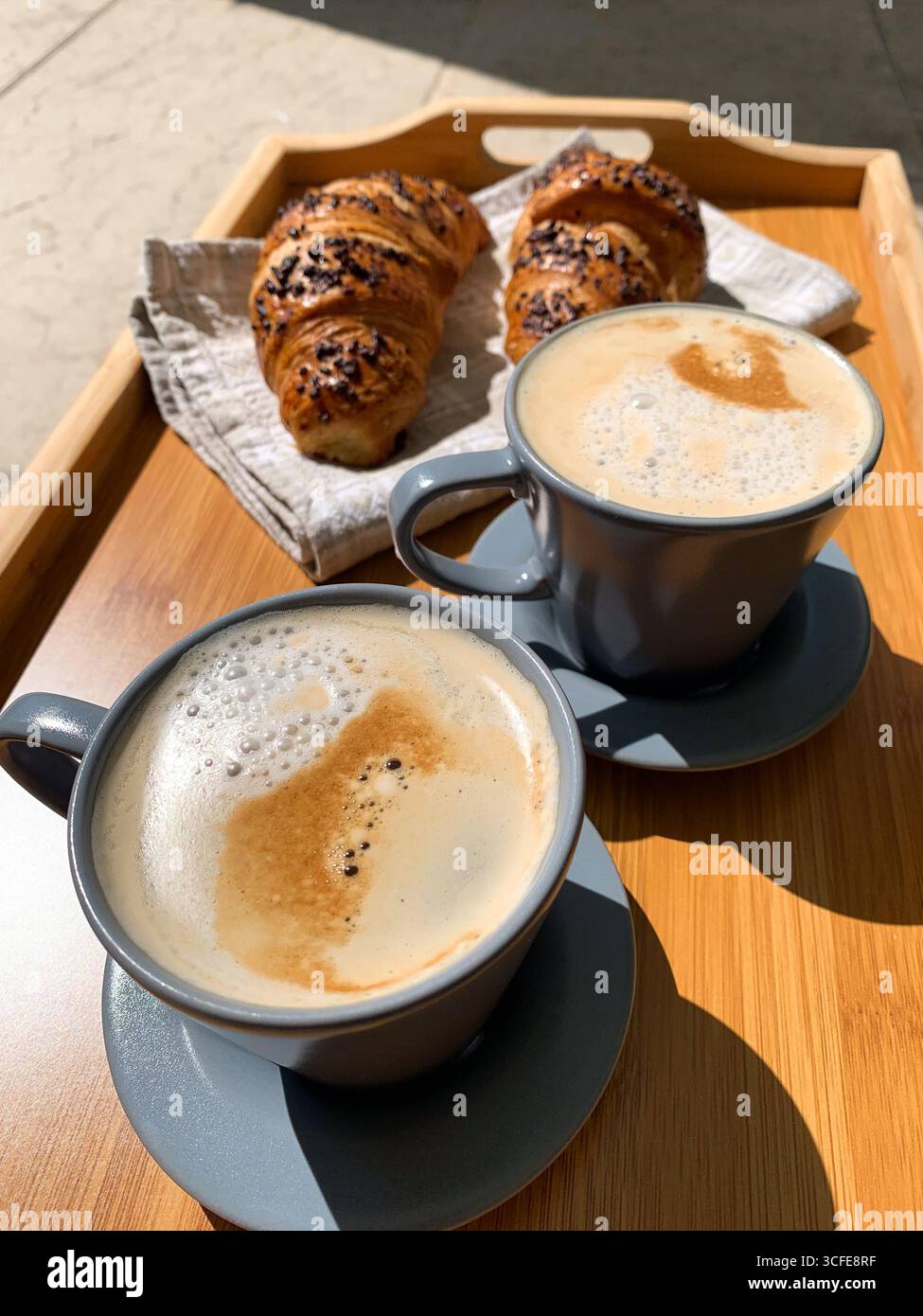 Traditional Italian breakfast. Fresh croissants and cappuccino on a wooden tray. European food and pastry. Morning meal and cozy home breakfast. - Smartphone Captured Stock Image