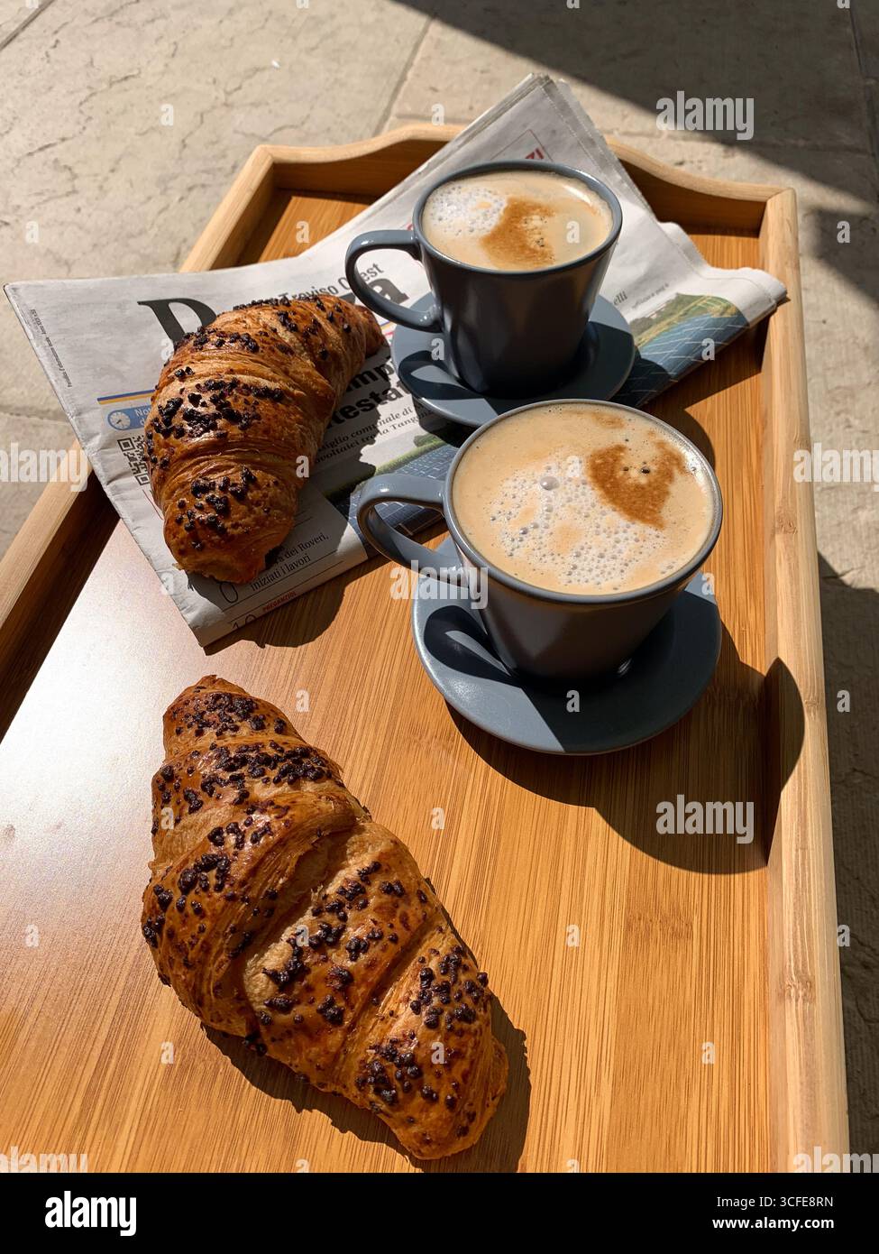 Traditional Italian breakfast. Fresh croissants and cappuccino on a wooden tray. European food and pastry. Morning meal and cozy home breakfast. - Smartphone Captured Stock Image