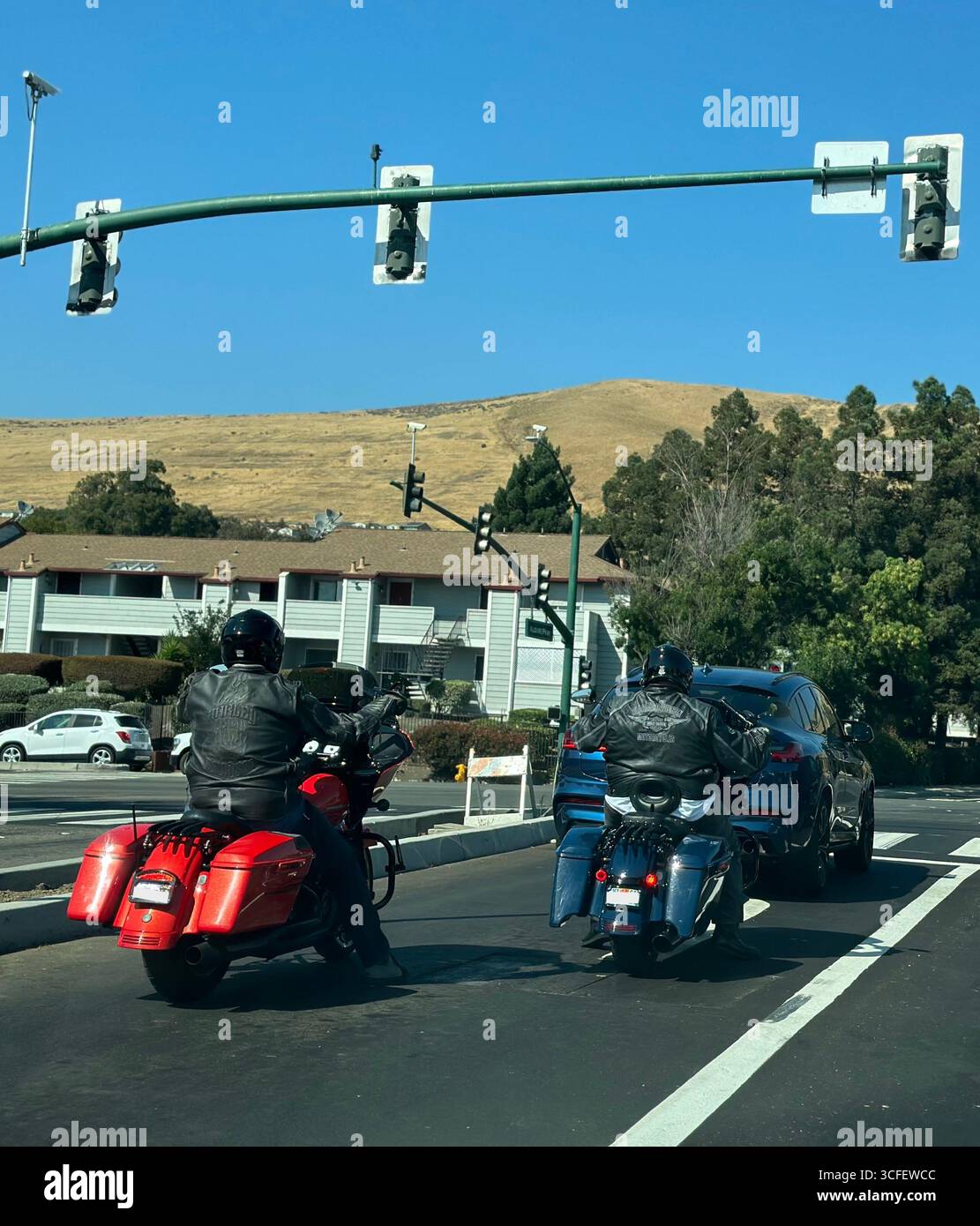 Motorcyclists in leather jackets riding on urban road in California Stock Photo