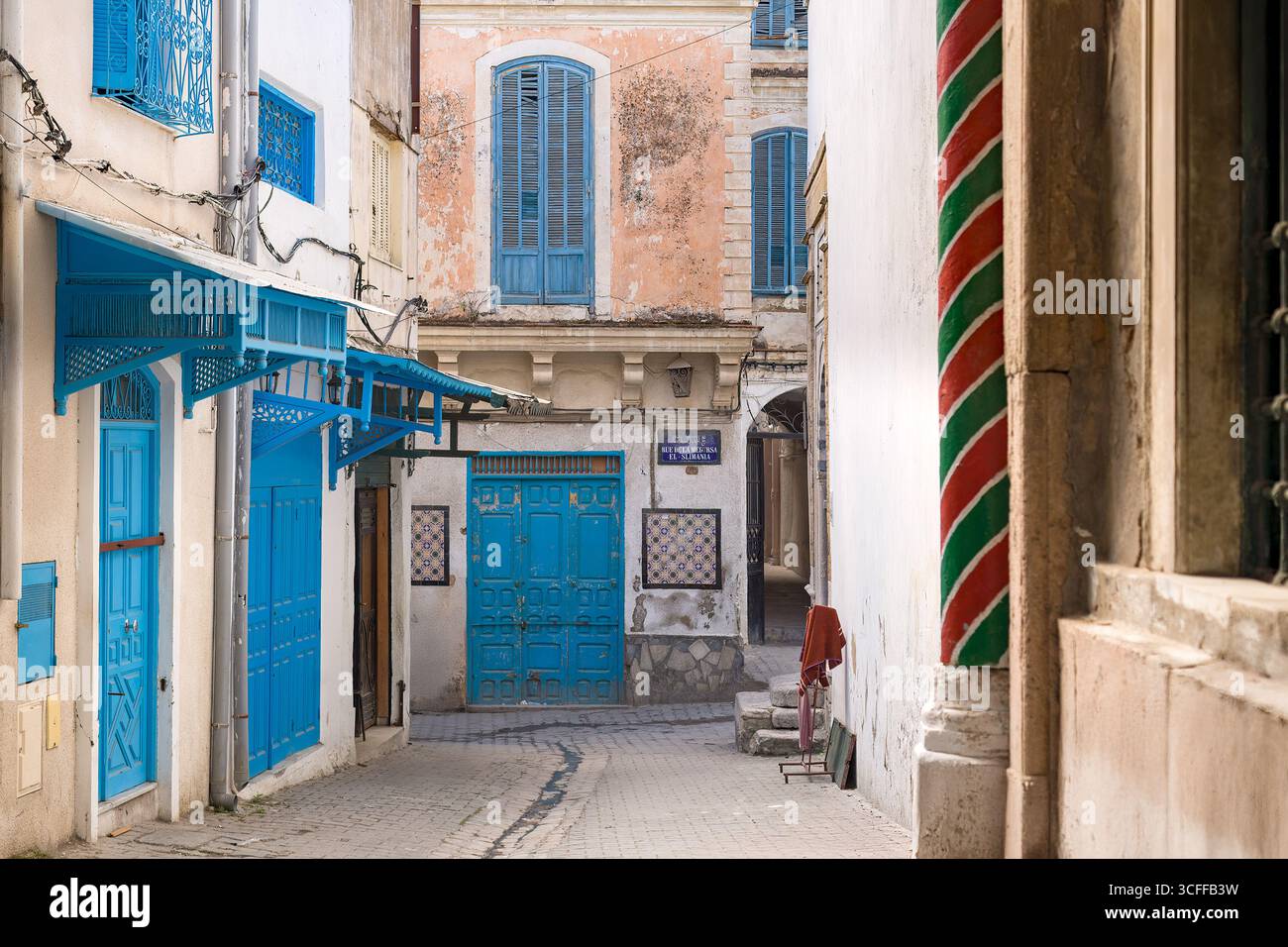 A quiet street in the historic Medina quarter of Tunis, with old buildings and traditional blue doors. Stock Photo