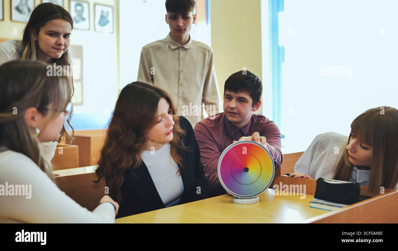 Students in physics class spin Newton's multicolored disk. Stock Photo
