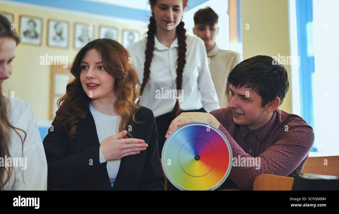 Students in physics class spin Newton's multicolored disk. Stock Photo