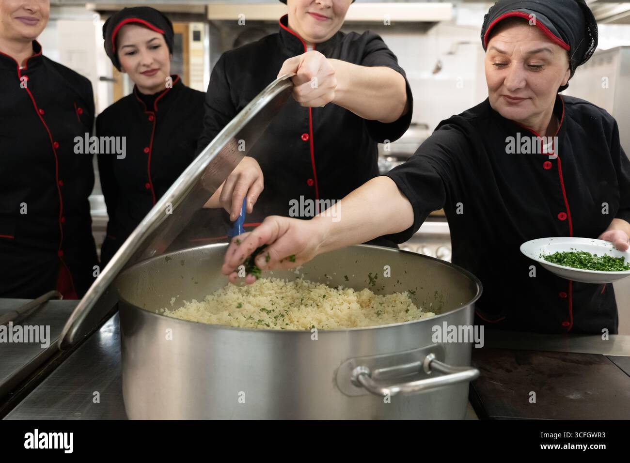 Chef Using Pot Group of chefs in black uniforms preparing rice in a large pot in a ...