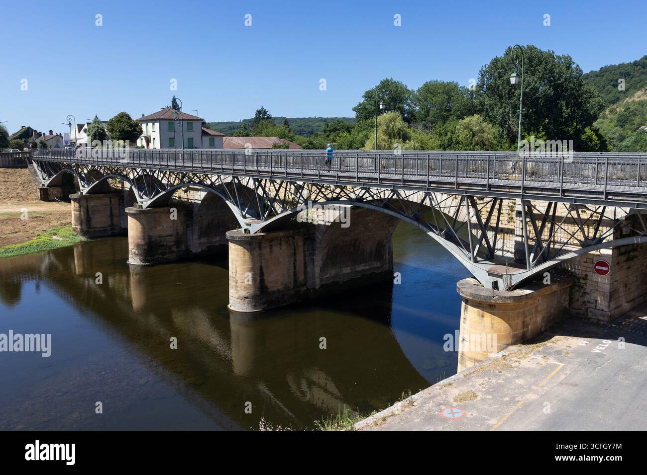 The arched bridge and pedestrian bridge across the Vezere River at Le Bugue in the Dordogne, France. - Stock Image