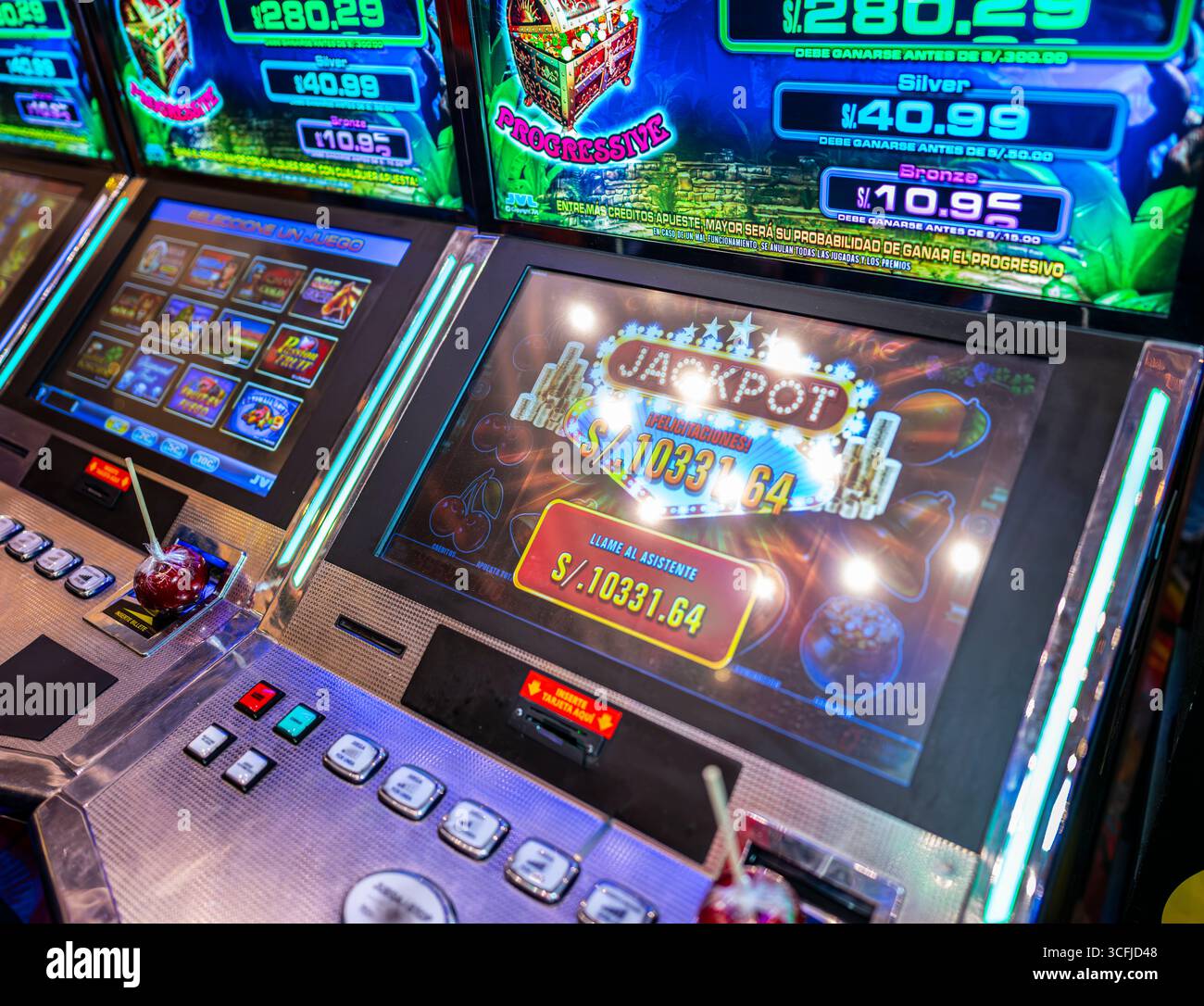 Close-up of slot machine screen showing jackpot prize inside casino with bright lights, buttons, and candy apple placed on the machine. Stock Photo