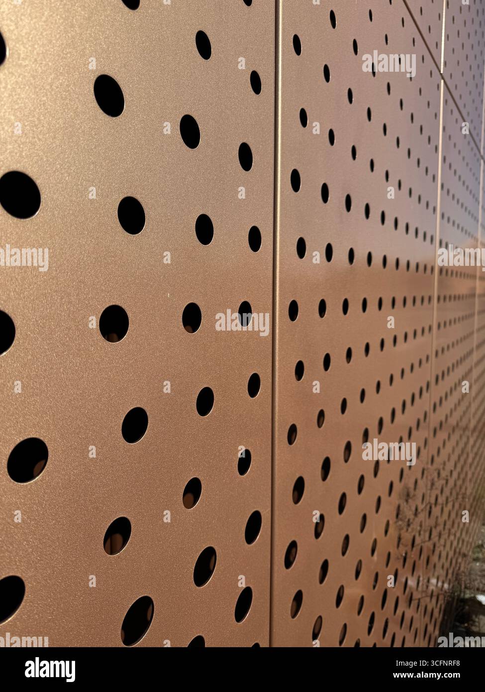 A patterned metal surface with circular holes, blends aesthetics and function in design Stock Photo