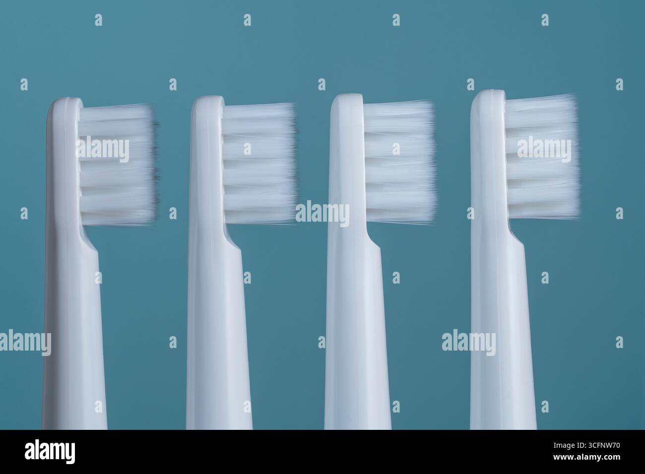 Four white plastic toothbrushes on a blue background, close up Stock Photo