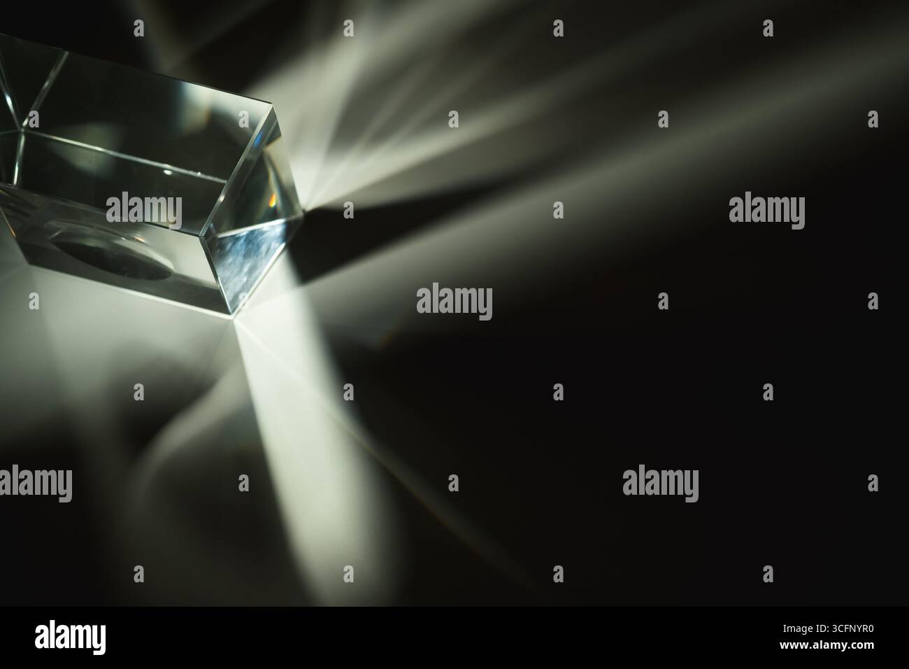 A photo capturing the stunning light refractions created by a glass prism on a white background, showcasing a spectrum of colors and optical beauty Stock Photo