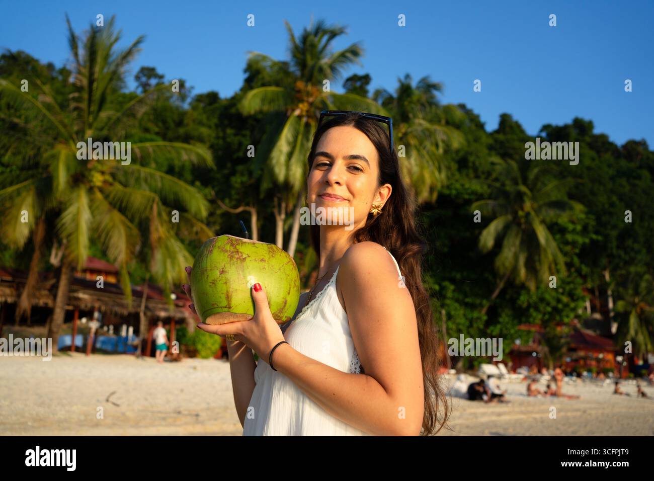 Young woman enjoying a refreshing coconut on a beautiful tropical beach Stock Photo
