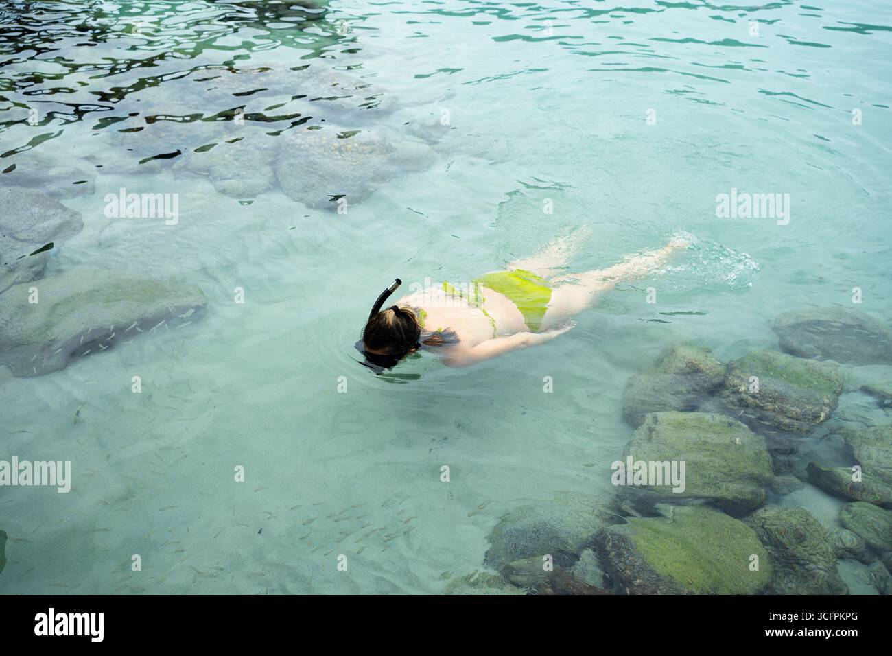 Woman snorkeling in shallow water near rocks, enjoying summer vacation Stock Photo