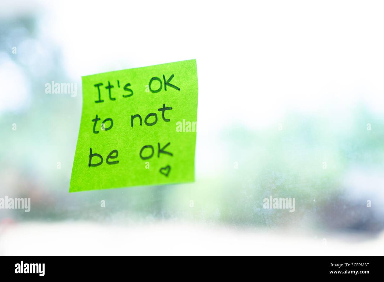 Close-up of a green sticky note with the encouraging message it's ok to not be ok providing comfort and validation during challenging times Stock Photo