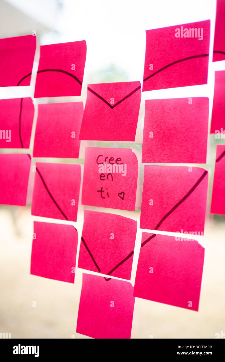 Pink sticky notes forming a heart shape with a motivational message in spanish, encouraging self-belief and positive thinking Stock Photo