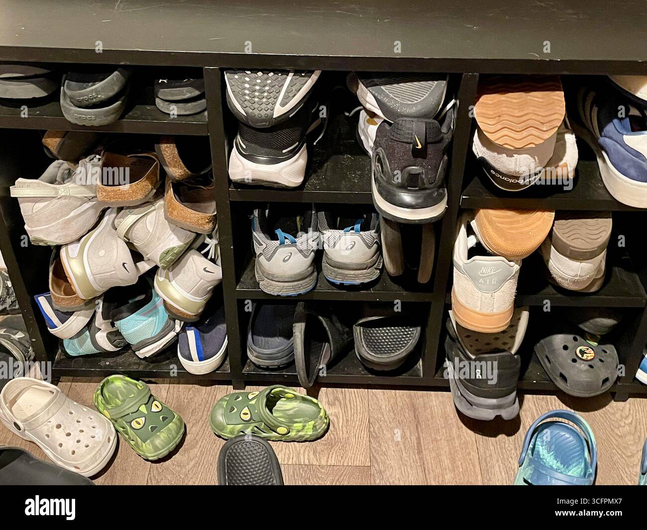 Storage cubbyholes filled with  large  family shoes at a residential home, 2025, Great Falls, Montana, USA - Smartphone Captured Stock Image
