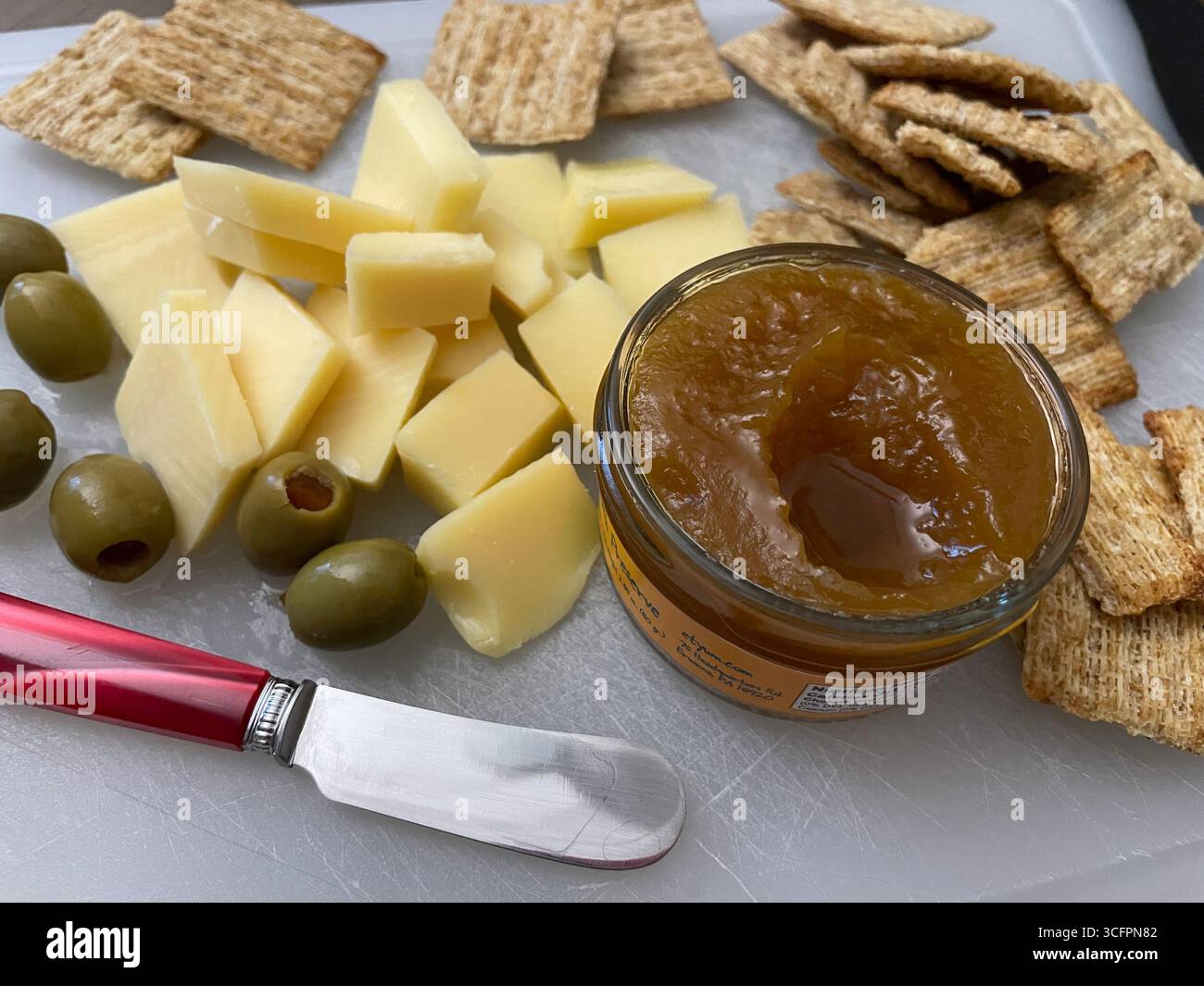 Still life of an hors d'oeuvre platter consisting of spreadable jam, sliced Gouda cheese and green olives with Triscuit crackers, 2025, United States - Smartphone Captured Stock Image
