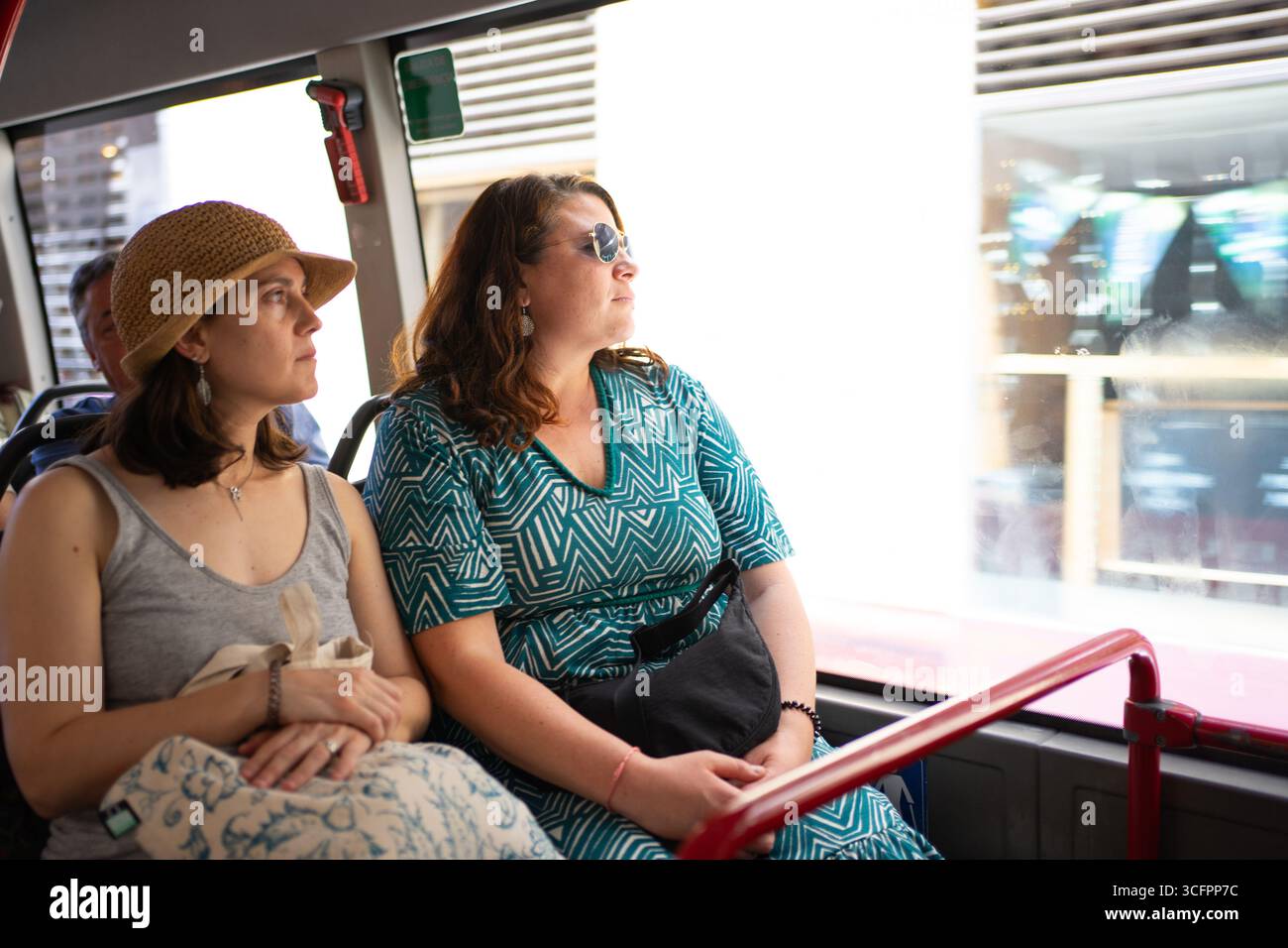 Two female tourists enjoying sightseeing tour, looking out bus window ...